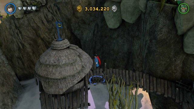 Pierwszy złoty klocek otrzymasz po zniszczeniu kilku niebieskich flag z logiem Batmana w wiosce - Złote Klocki | Odym - sekrety w Lego Batman 3 Poza Gotham - LEGO Batman 3: Poza Gotham - poradnik do gry
