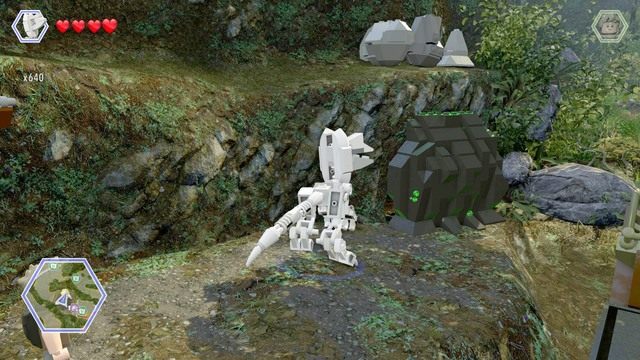 Po przedostaniu się na brzeg, zmień postać na dilofozaura i zniszcz blokujący dostęp do jaskini głaz - Kryjówka Erica | Jurassic Park III - sekrety - LEGO Jurassic World - poradnik gry