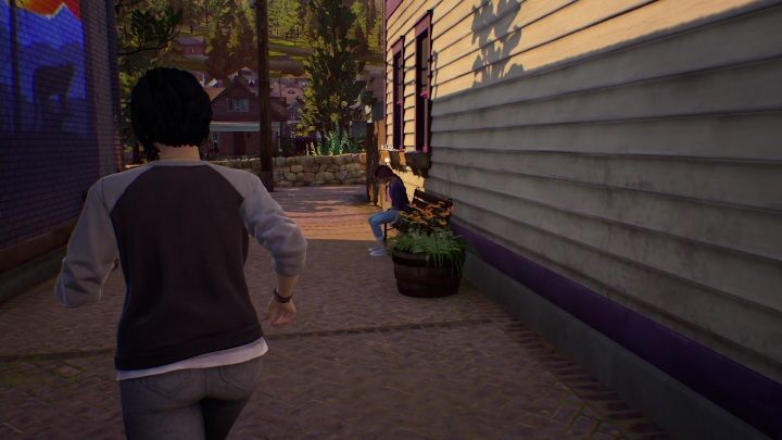 Riley siedzi na ławce, zaraz za sklepem Charlotte - Life is Strange True Colors: Mac - solucja, opis przejścia - Life is Strange True Colors - poradnik do gry