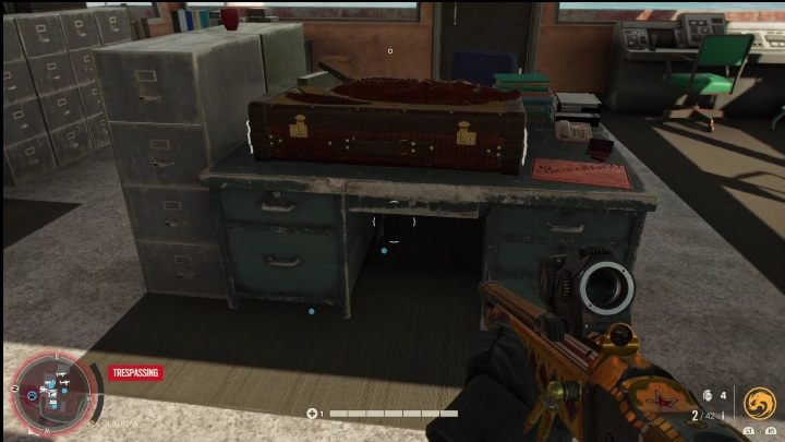 Skrzynia leży na metalowym biurku, w pomieszczeniu przy brzegu zbiornika wodnego - Far Cry 6: Karabiny, Unikalne bronie - lista - Far Cry 6 - poradnik do gry