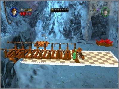 Przejdź po drewnianej barierce w prawo i użyj bicza na krawędzi, w podświetlonym miejscu - Chapter 2 - Into the Mountains (cz.1) - Poszukiwacze Zaginionej Arki - LEGO Indiana Jones: The Original Adventures - poradnik do gry